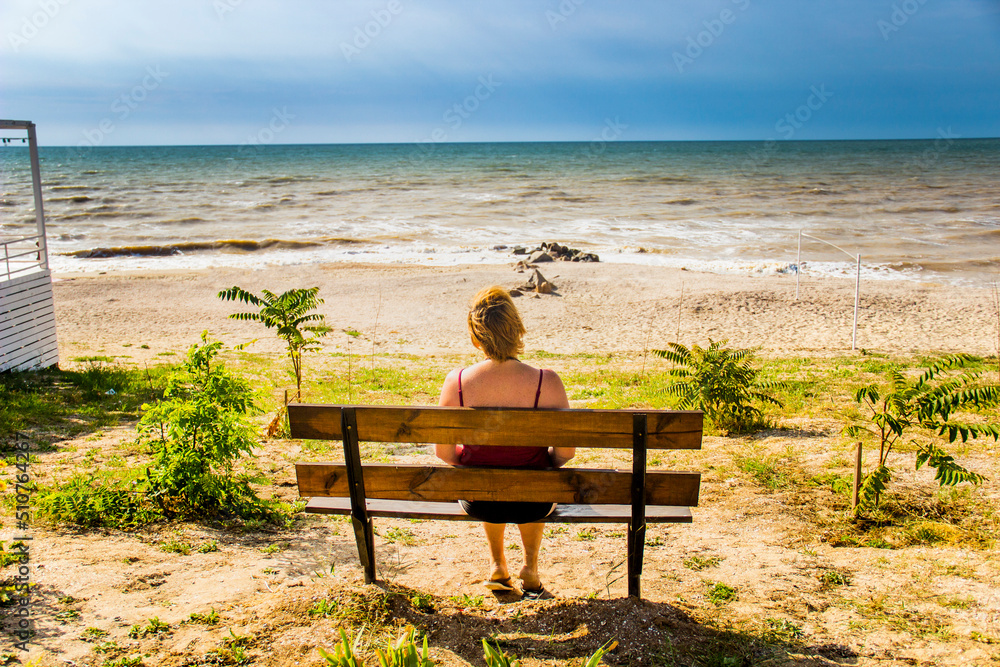 a woman sitting on the bench and looking at the sea a woman sitting on the bench and looking at the sea