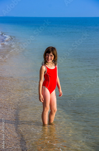 little girl in a red bathing suit on the sea