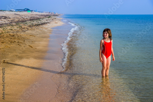 little girl in a red bathing suit on the sea