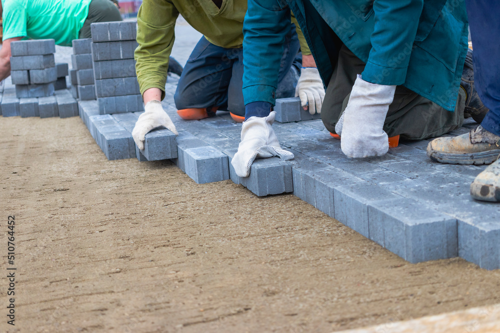 Laying gray concrete paving slabs in house courtyard driveway patio