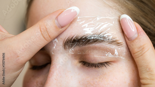 The master uses a plastic film during lamination of the eyebrows.