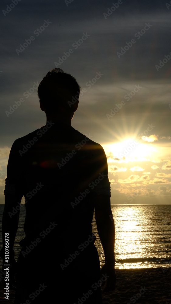 Silhouette young man looking at sea while sunset view on beach.