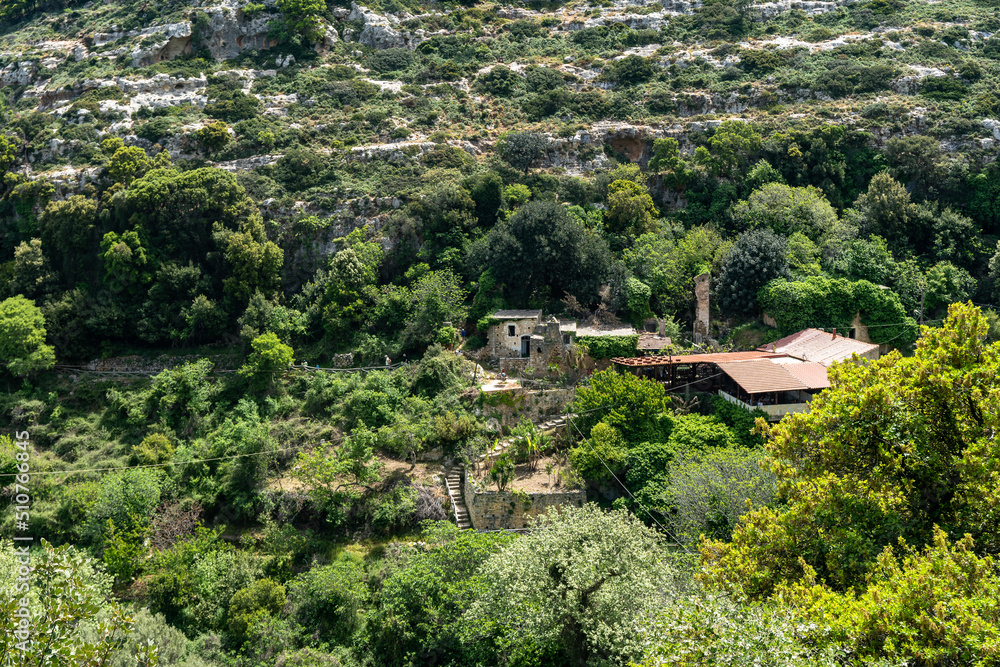 Beautiful mountain, cliff, limestone rock covered with forest. Mediterranean landscape. Old abandoned villa in the mountains at the top. Greece, Rethymnon area.