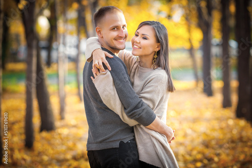 Young international couple hugging on a date in autumn city park.