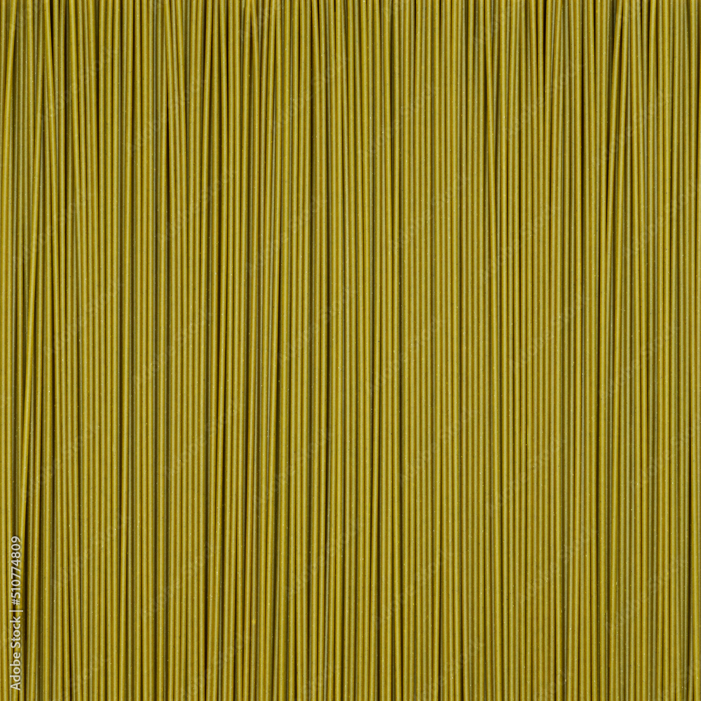 Fototapeta premium green long raw spaghetti background. spinach noodles. square