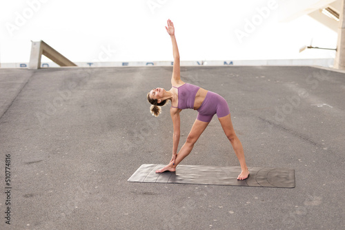 Beautiful young woman practising yoga outside. Fit woman doing yoga stretching exercises.. © JustLife