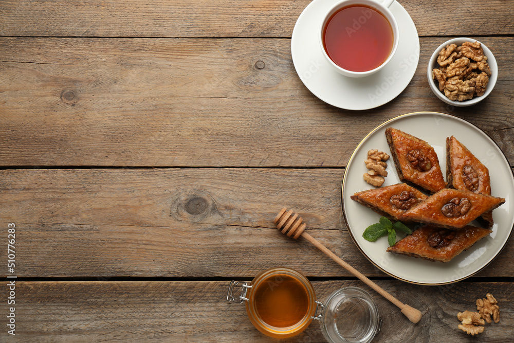 Delicious honey baklava with walnuts served on wooden table, flat lay. Space for text Delicious honey baklava with walnuts served on wooden table, flat lay. Space for text