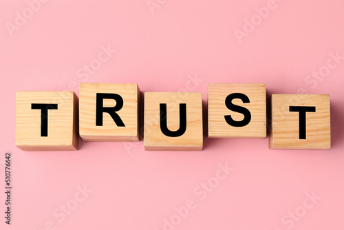 Foto Cubes with word TRUST on pink background, flat lay