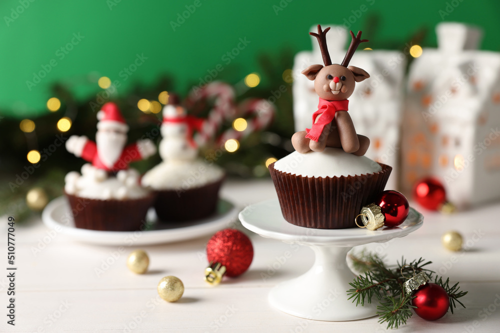 Tasty cupcake with Christmas reindeer figure on white wooden table. Space for text