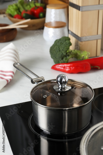 Metal saucepan on cooktop in kitchen. Cooking utensils