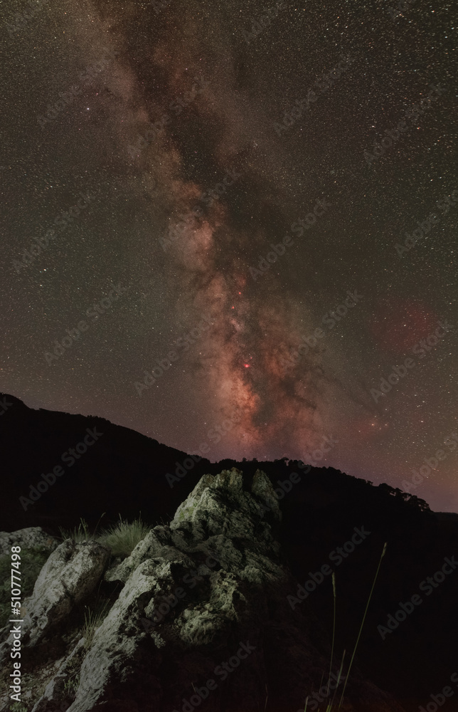 Vertical Milky Way panorama above jagged mountain ridge