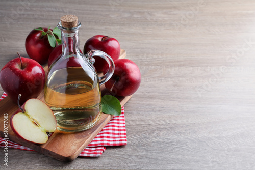 Jug of tasty juice and fresh ripe red apples on wooden table, space for text photo