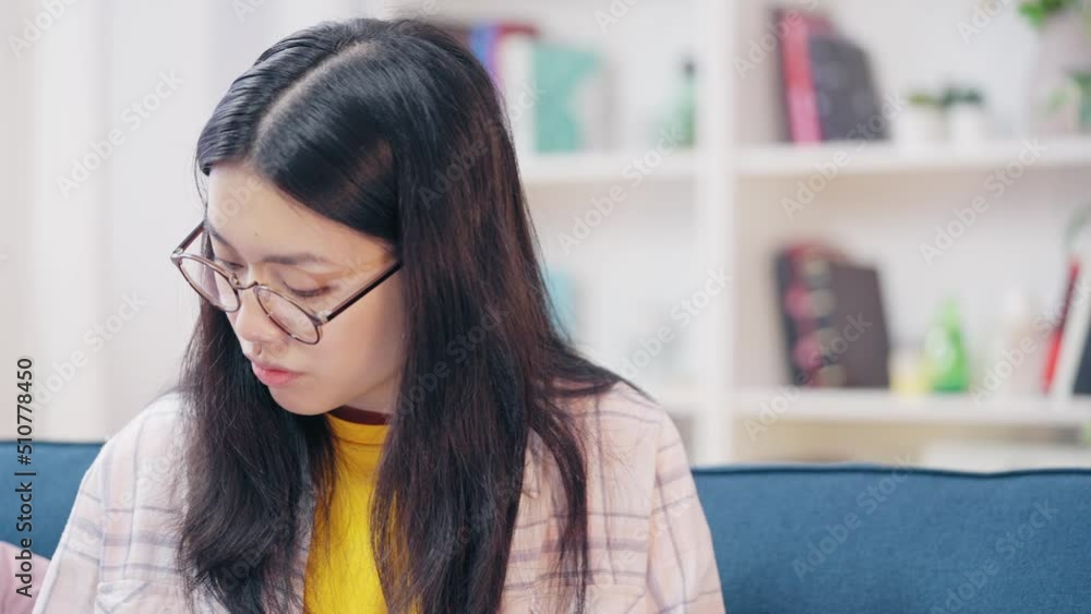 Asian woman in eyeglasses working on laptop at home, online school, freelancing Asian woman in eyeglasses working on laptop at home, online school, freelancing