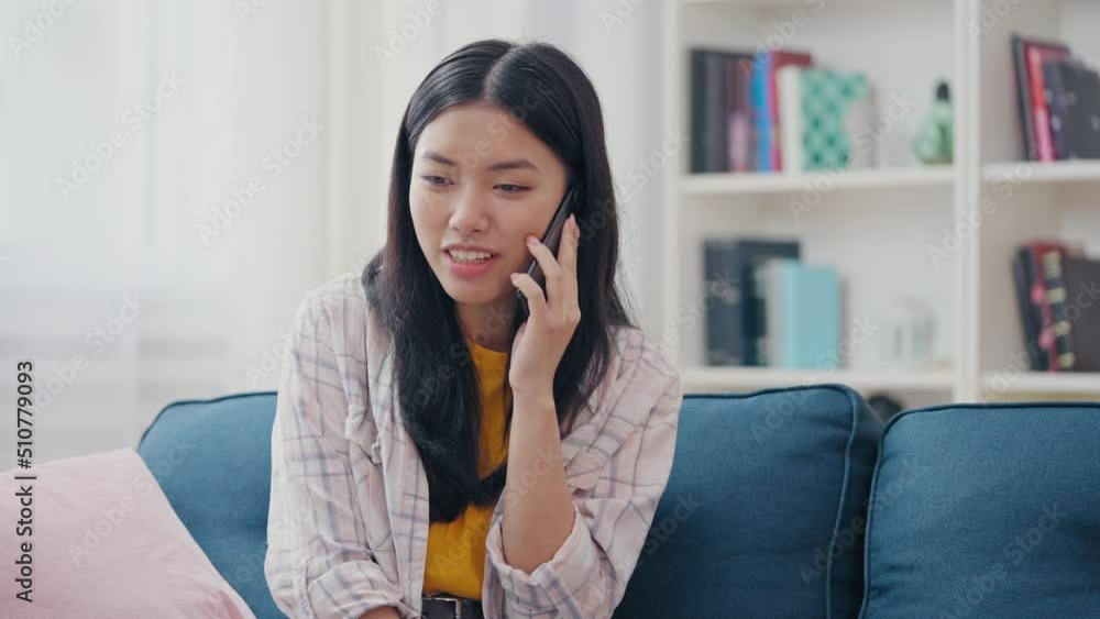 Cheerful Asian woman talking on cellphone at home, communication and gadgets Cheerful Asian woman talking on cellphone at home, communication and gadgets