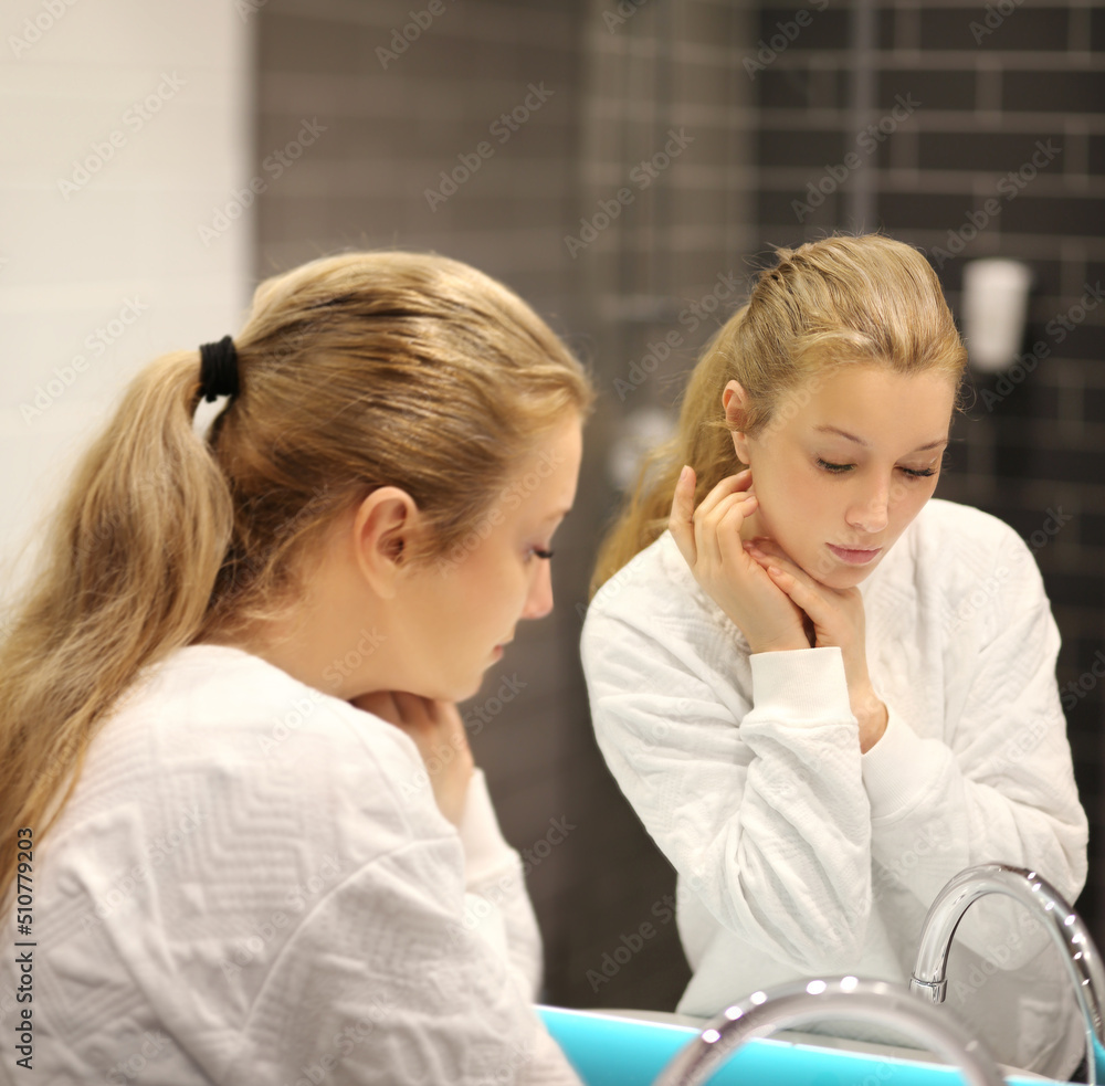 woman looking in the mirror in the bathroom and taking care of her skin.Applying the cream..Magic anti-aging cream. woman looking in the mirror in the bathroom and taking care of her skin.Applying the cream..Magic anti-aging cream.