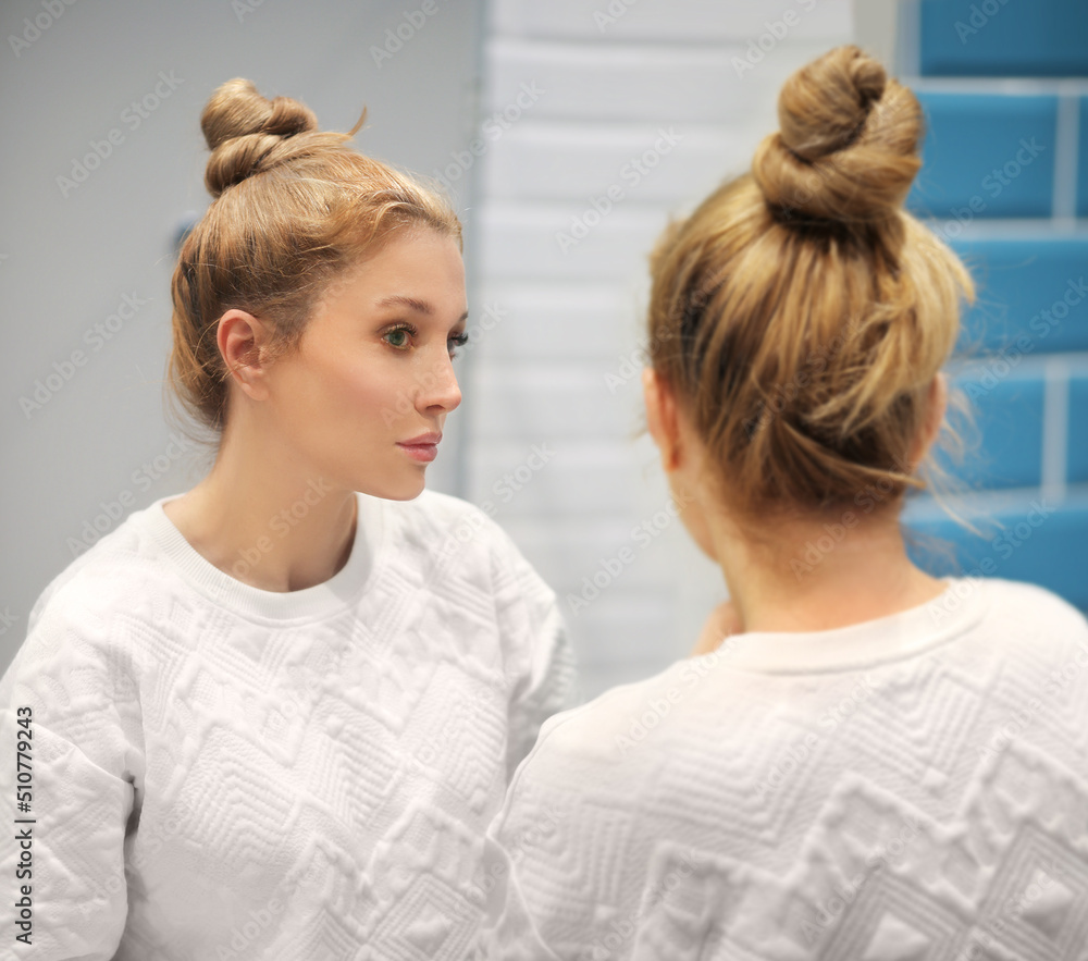 woman looking in the mirror in the bathroom and taking care of her skin.Applying the cream..Magic anti-aging cream. woman looking in the mirror in the bathroom and taking care of her skin.Applying the cream..Magic anti-aging cream.