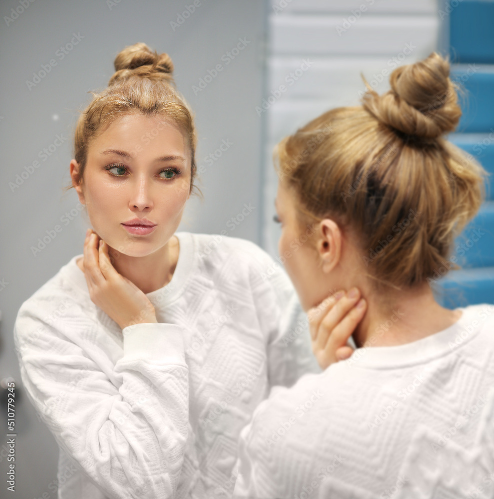 woman looking in the mirror in the bathroom and taking care of her skin.Applying the cream..Magic anti-aging cream. woman looking in the mirror in the bathroom and taking care of her skin.Applying the cream..Magic anti-aging cream.