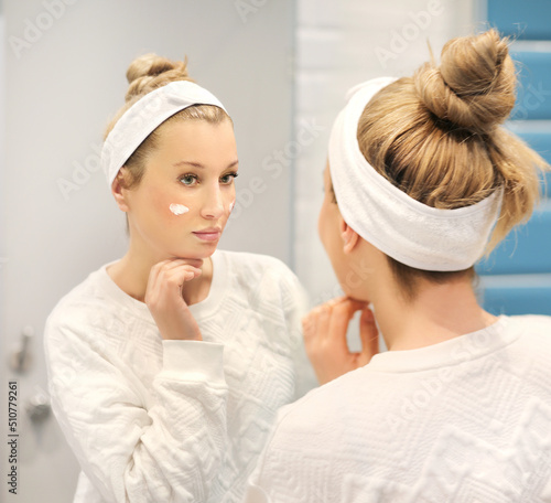 woman looking in the mirror in the bathroom and taking care of her skin.Applying the cream..Magic anti-aging cream.