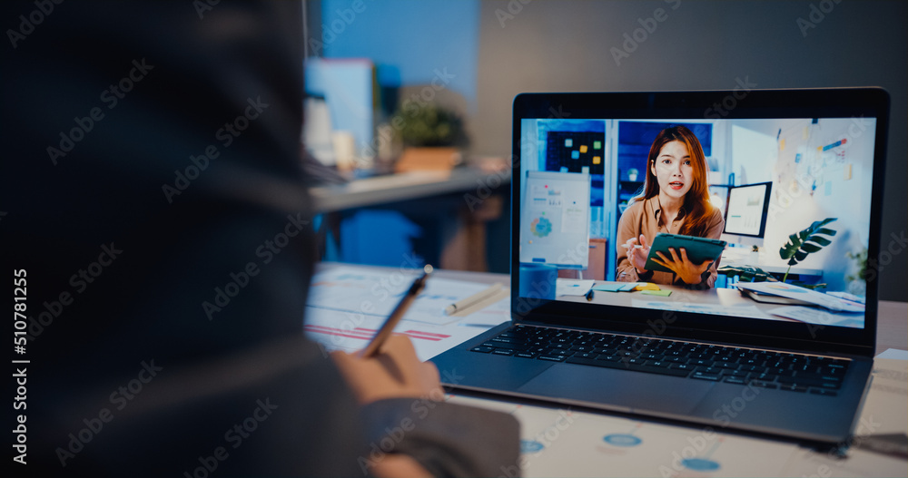 Asia businesswoman using laptop talk to colleagues about plan in video call meeting at living room at home. Working from house overload at night, remotely, social distance, quarantine for coronavirus. Asia businesswoman using laptop talk to colleagues about plan in video call meeting at living room at home. Working from house overload at night, remotely, social distance, quarantine for coronavirus.