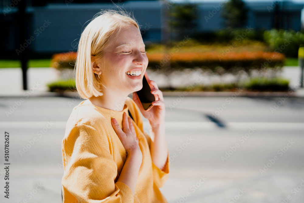 Happy girl walking on the street using the phone. Beautiful blonde girl talking to the smartphone Happy girl walking on the street using the phone. Beautiful blonde girl talking to the smartphone