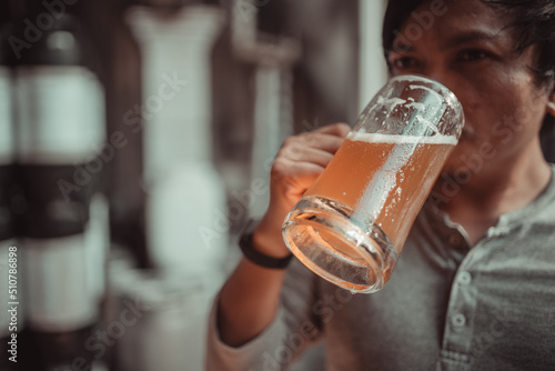 Платно Asian man raising a glass of craft beer drinking