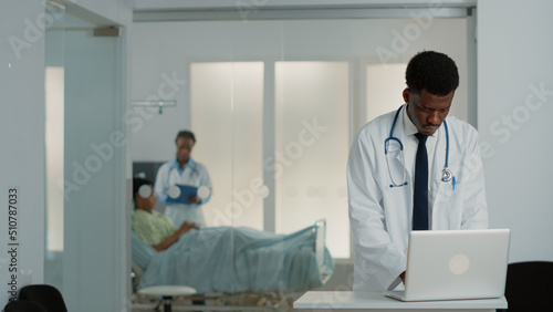 General practitioner looking at modern laptop to work on medical treatment and healthcare system. Physician using device to find checkup information to cure patient with disease.