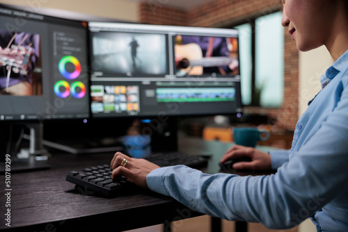 Close up shot of professional videographer sitting at desk while enhancing movie footage using specialized software. Creative company film editor expert sitting at multi monitor workstation.