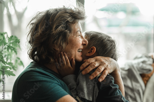 Grandmother and grandson spend time together, horizontal shot, the grandmother is no longer alone, smiling happily and hugging her little grandson photo