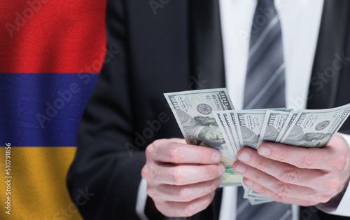 Hands holding dollar money on flag of Armenia