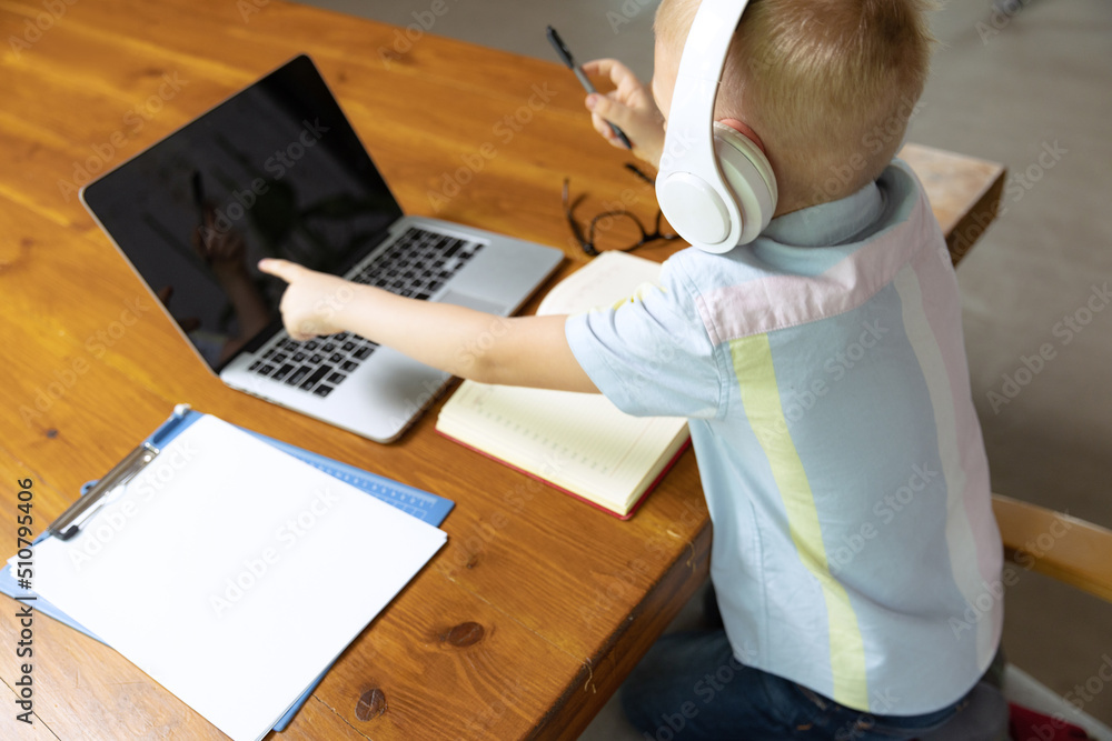 Little boy, school age kid doing homework, using laptop at home interior. Education, childhood, people, homework and school concept. Little boy, school age kid doing homework, using laptop at home interior. Education, childhood, people, homework and school concept.