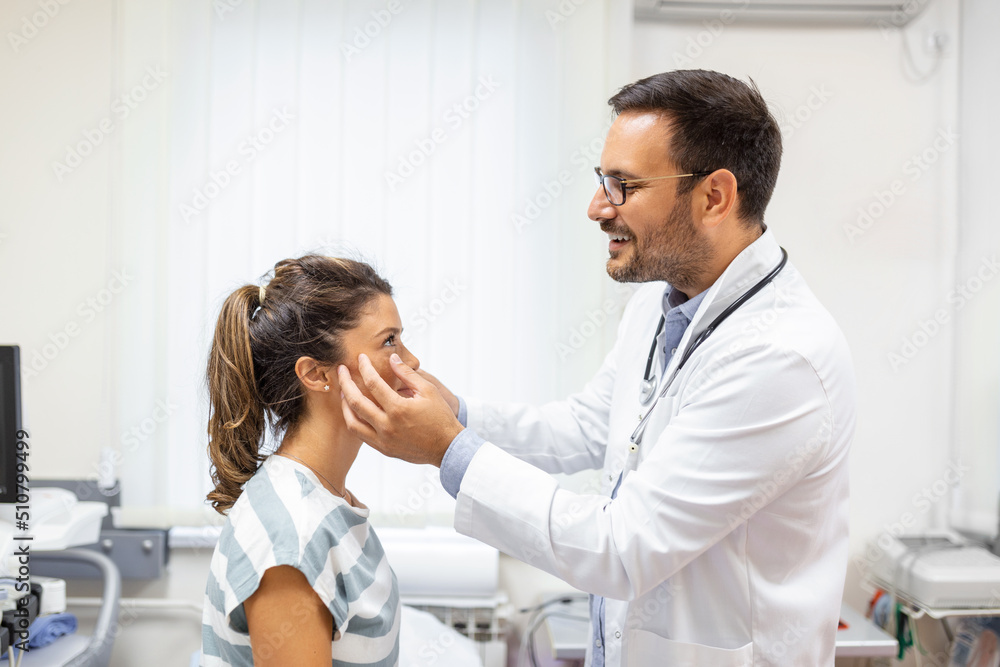 Fototapeta premium Adult woman having a visit at oculist's office. Doctor examining eyes of young woman in clinic.
