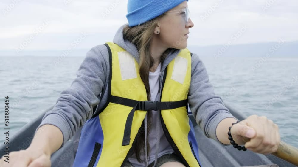 Girl in a life jacket, in a blue cap and sunglasses is riding a boat on the lake Girl in a life jacket, in a blue cap and sunglasses is riding a boat on the lake