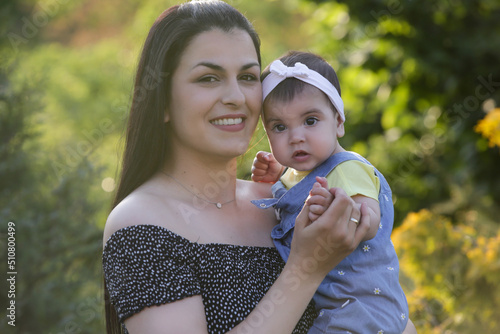 Young mother enjoying a idyllic summer day outdoor with her baby girl. Family portrait in the park. 