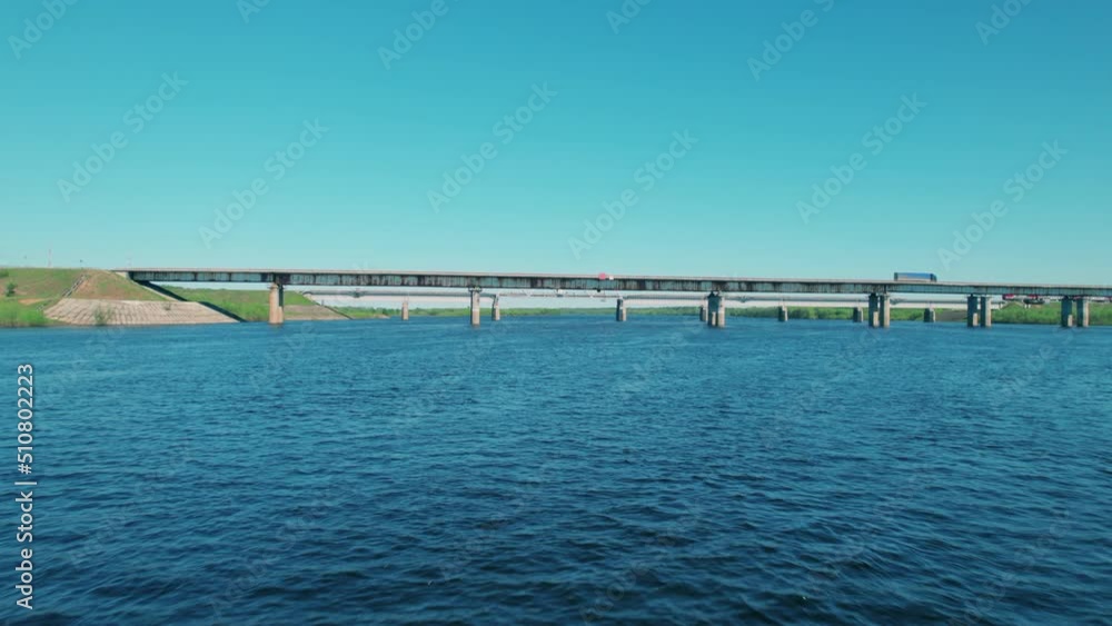 Shot on a drone. Road and railway bridges. The train goes over the bridge over the river. Engineering structure for the transport . Shot on a drone. Road and railway bridges. The train goes over the bridge over the river. Engineering structure for the transport .
