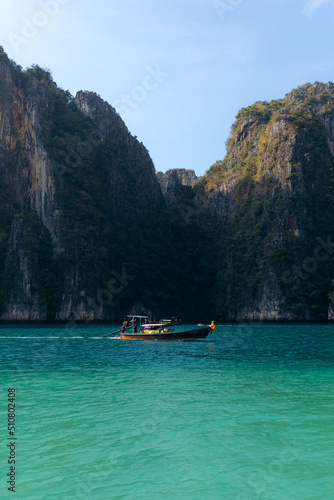 Long tail boat cruising through the turquoise waters of Koh phi phi led lagoon in Thailand
