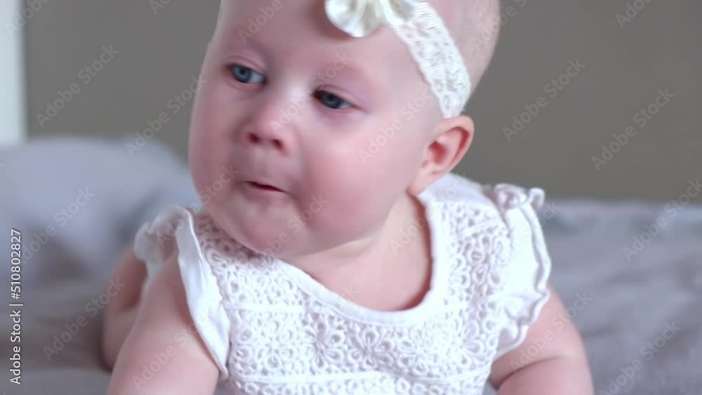 Cute little baby girl lies on her stomach on the bed and looking at the camera and smiles. Cute little baby girl lies on her stomach on the bed and looking at the camera and smiles.