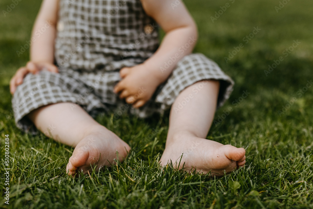 Closeup of baby sitting on grass with barefoot feet. Closeup of baby sitting on grass with barefoot feet.