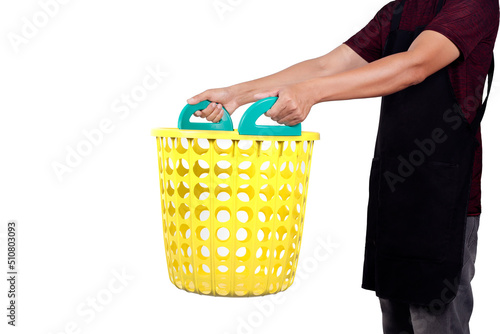 Man wearing black apron holding empty yellow basket with green handles isolated on white background.