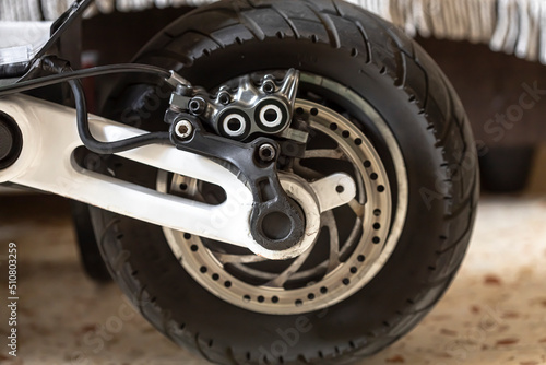 The rear wheel of an electric scooter with the brake drum and motor visible. Transport.