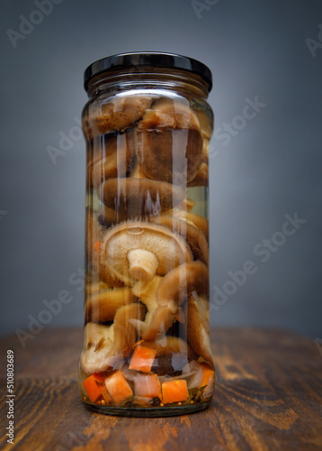 Pickled mushrooms with vegetables in a glass jar . Salted homemade mushrooms . Rustic food . photo