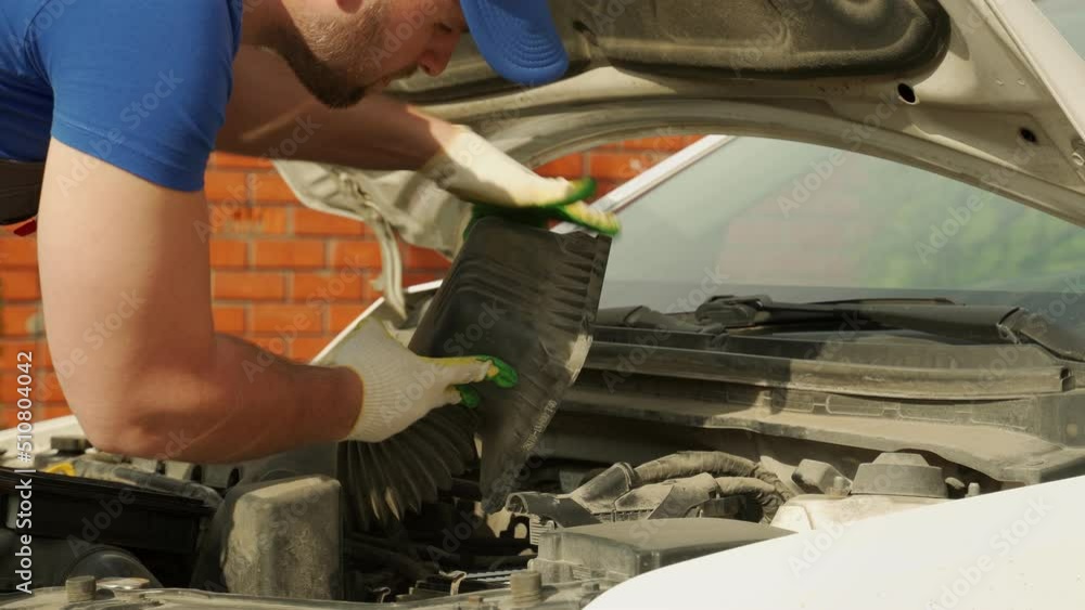 Man in work gloves checks satisfactory state of car engine air filter closeup. Diagnosis of internal spare parts of car and serviceability outdoors Man in work gloves checks satisfactory state of car engine air filter closeup. Diagnosis of internal spare parts of car and serviceability outdoors