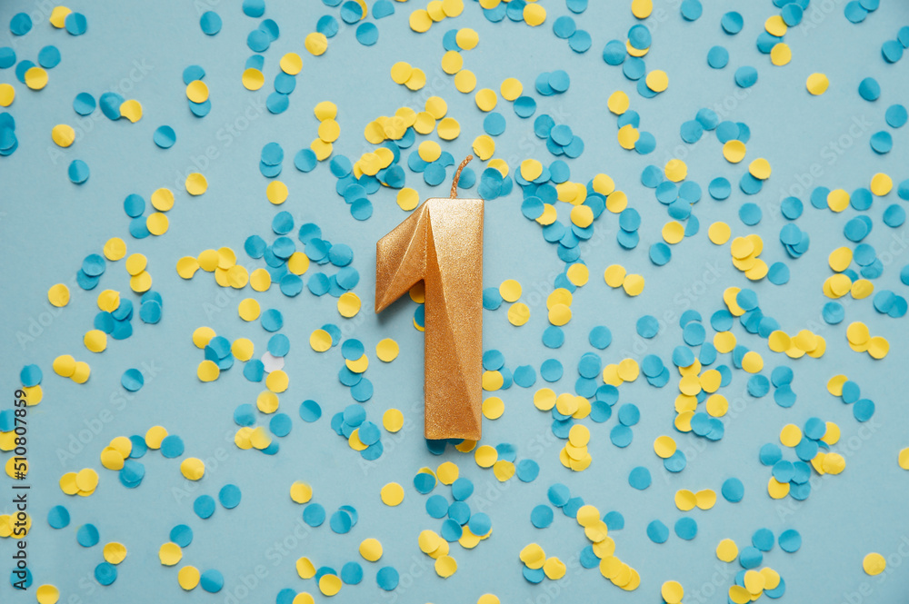 Number 1 one golden celebration birthday candle on yellow and blue