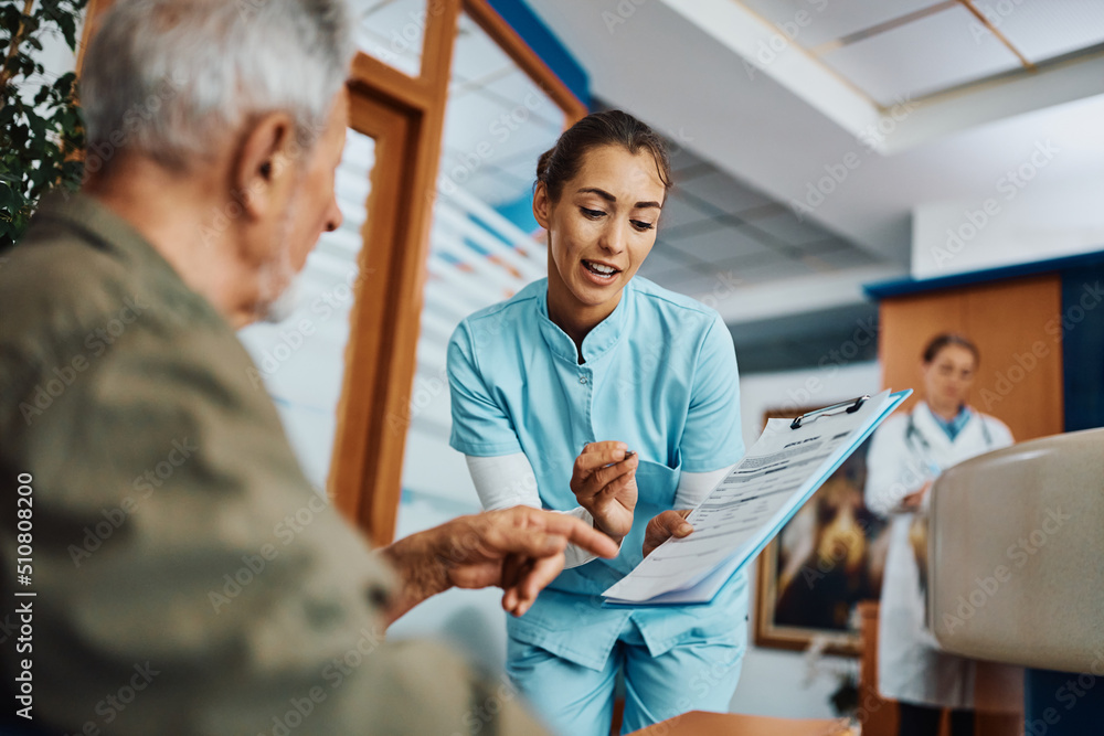 Young nurse assisting senior man in filling paperwork at doctor's office. Young nurse assisting senior man in filling paperwork at doctor's office.