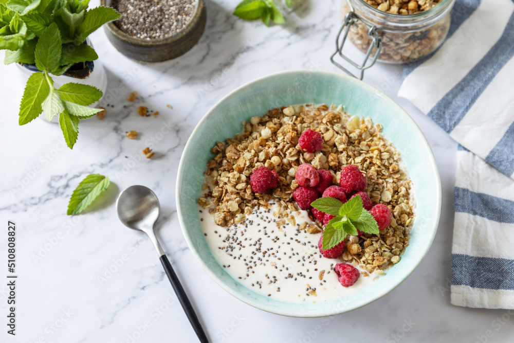 Breakfast, sweet dessert. Diet nutrition concept. Homemade granola with yogurt, chia seeds and raspberry on a marble tabletop. Breakfast, sweet dessert. Diet nutrition concept. Homemade granola with yogurt, chia seeds and raspberry on a marble tabletop.