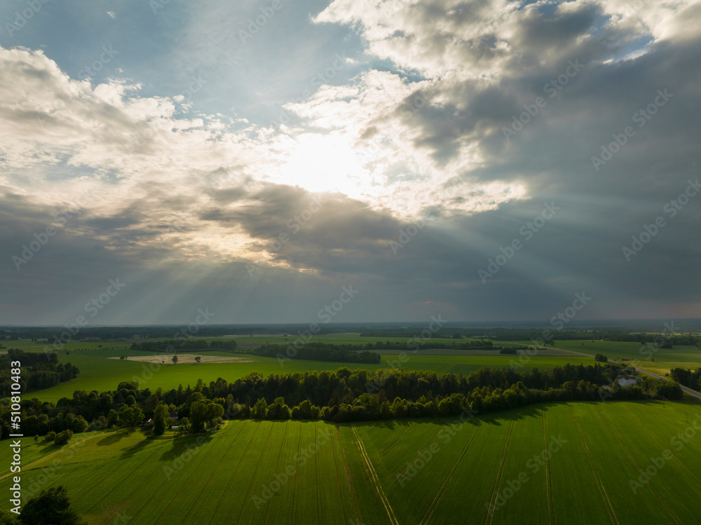 The sun's rays pass through the clouds, the earth's path divides the green fields The sun's rays pass through the clouds, the earth's path divides the green fields