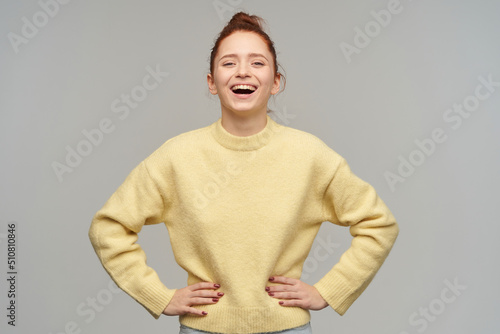 indoor studio portrait of young ginger female with freckles posing over grey background laugh and looking into camera