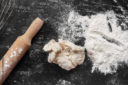 Scattered flour with rolling pin on black background