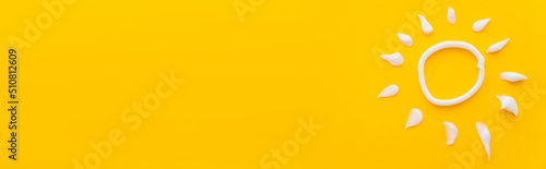 Tableau sur toile Top view of white sun sign from sunscreen cream on yellow background, banner
