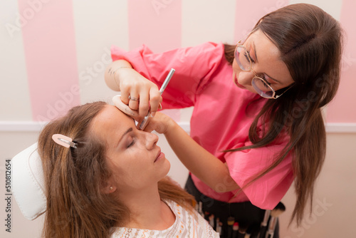 A beautician works carefully and with skill with the eyeliner cosmetic pencil, in order to achieve the best results for her client during a make up session at the beauty salon