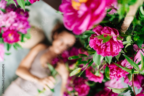 focus on flowers. an attractive woman on the floor with a bouquet of peonies.